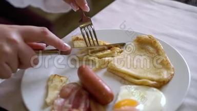 早上吃早餐的女人。 盘子里有<strong>煎鸡蛋</strong>，<strong>煎</strong>饼和香肠。
