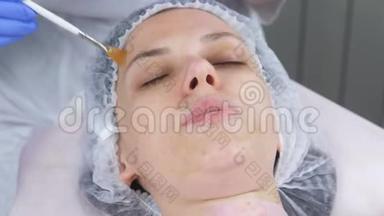 美容师用刷子把面具戴在女人`脸上。 戴着蓝色橡胶手套的美容师的手。 面部