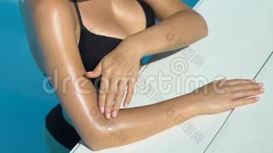 <strong>比基尼女士</strong>抚摸皮肤，使用防晒霜，在游泳池休息