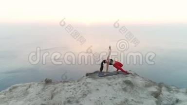 美丽的女人正在做瑜伽，Vasisthasana，山顶的侧帆船，日落时的海景。