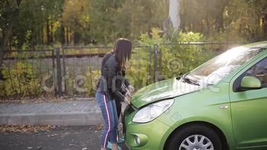 两个女孩试图打开汽车引擎盖给一个死电池充电