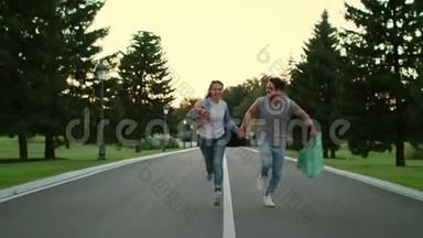 快乐的一对情侣牵着手在夏天公园的路上奔跑