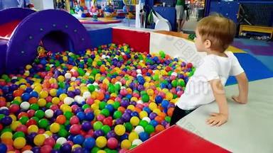 4k小男孩在游乐场玩游戏的视频，里面装满了五颜六色的塑料球