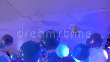 在一个生日聚会上沿着气球的背景慢动作。 派对上的蓝色气球在夜总会的灯光下点燃音乐。