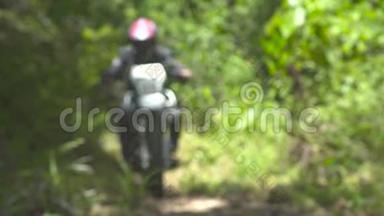 在夏季森林里骑摩托车的摩托车手。在林间小路上关闭摩托车轮子。摩托车手继续行驶