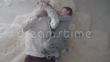 快乐的父亲和儿子在白色的毛皮地毯上玩<strong>钱</strong>玩得很<strong>开心</strong>。 娱乐爸爸和孩子。 父亲