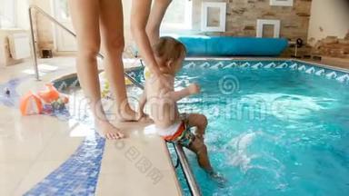 4k录像，年轻母亲把她刚学会走路的儿子放在健身房的游泳池里