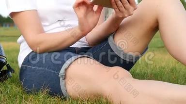<strong>女孩</strong>坐在绿草上，使用智能手机。 一个年轻的女人使用<strong>社交网络</strong>。 特写