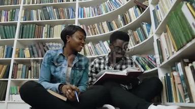 非洲男女学生看书，准备考试，坐在书架旁边的地板上