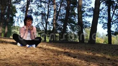 一个女孩坐在公园里看着她的智能手机。 互联网、社交网络和博客。