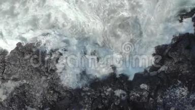 黑色火山海滩的空中拍摄。 波浪撞击岩石，形成天然喷泉
