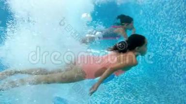 两个十几岁的女孩牵着手在游泳池里4k视频。 从水下看。 儿童游戏