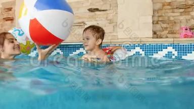4k视频快乐妈妈带孩子在室内游泳池玩充气彩色沙滩球