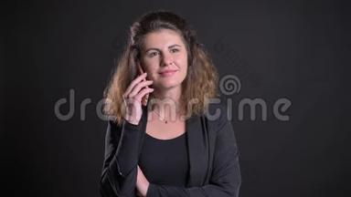 超重的高加索女人在<strong>黑色背景</strong>下用手机微笑交谈的特写<strong>照片</strong>。