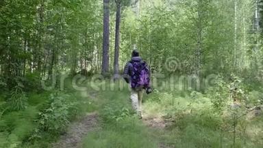 一个男人带着一个大型<strong>旅游</strong>背包穿越树林，生态<strong>旅游</strong>的概念。