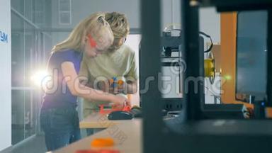 孩子们用3D打印机工作。 男孩和女孩在一个有<strong>印刷设备</strong>的科学实验室工作。