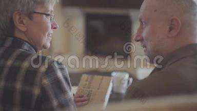 老夫妇的<strong>背影</strong>，<strong>男人</strong>和女人，坐在沙发上拿着一本书，互相交谈和微笑。 家庭