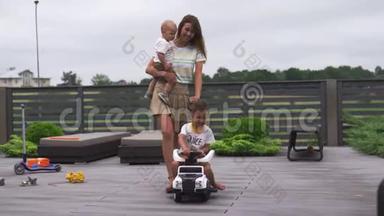 年轻的母亲在绿色的花园里和她的小男孩儿子兄弟一起玩，带着汽车-家庭价值观温暖