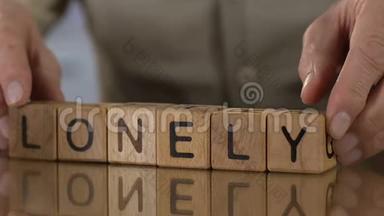 孤独的，年长的男人在做木头方块的字，人们在退休的家里