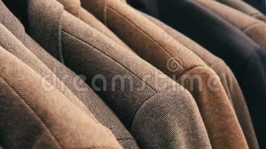 在商场的一家男士服装店，一排暖男`夹克衫在衣架上。 各种男士`西装挂在购物中心