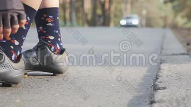 活泼的女孩在训练前收紧黑色和灰色的道路自行车鞋。 慢动作