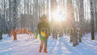 穿着深色冬季夹克和带毛衣的年轻人从寒冷中跳下来，并试图在带有桦树的图案城市公园<strong>保暖</strong>