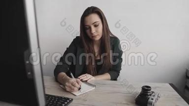 女商人在笔记本上写东西。 <strong>创业</strong>女企业家学生在工作场所学习书写笔记