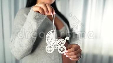 孕妇在一根绳子上拿着孕妇玩具婴儿车的象征. 家里有个大肚子的认不出来的女孩