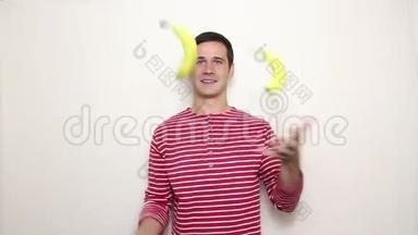 年轻的帅哥穿着一件条纹毛衣，笑容满面，穿着<strong>三根</strong>成熟的香蕉。