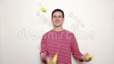 年轻的帅哥穿着一件条纹毛衣，笑容满面，穿着三根成熟的香蕉。