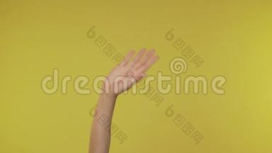 女人的手在4K演播室的黄色背景下挥手打招呼