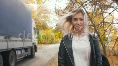 年轻漂亮的女孩走在秋天的跑道上，一个穿着<strong>皮夹克</strong>和运动服的年轻时髦女人走在沥青路上