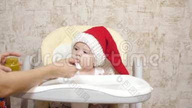 宝贝穿着红色<strong>圣诞老人帽子</strong>吃土豆泥。 妈妈给小<strong>圣诞老人</strong>喂粥。 戴圣诞帽的孩子