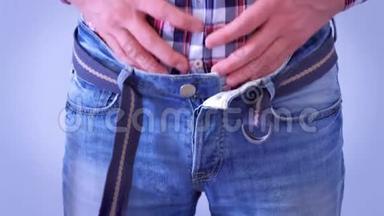 一个穿着紧身牛仔裤和腰带的人在吃了一顿丰盛的晚餐后抚摸着他的胃。