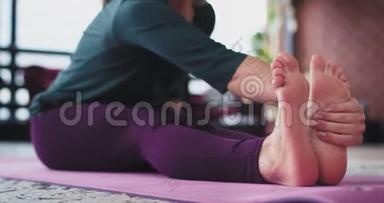 女士在家里练习瑜伽，她早上在瑜伽垫上伸展腿和身体