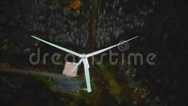 俯视无人机在绿色森林中的大型工作风车周围闲逛，替代可再生能源的概念。