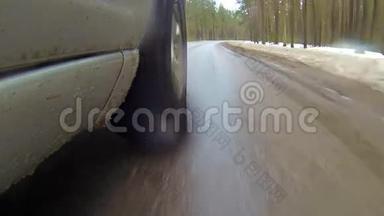 在森林的冬季道路上行驶时，摄像机安装在汽车上。 它会变成雪。 水溅到镜头上。