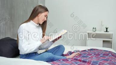 摘要：年轻女学生阅读教科书，并在家中的床上微笑全镜头