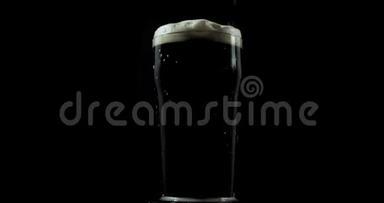 在一家私人啤酒厂为节日制作的深色工艺啤酒被倒入一个在黑色背景上旋转的玻璃杯中
