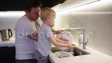 小男孩洗脏盘子。 孩子在家做清洁的同时，还要清洗陶器。
