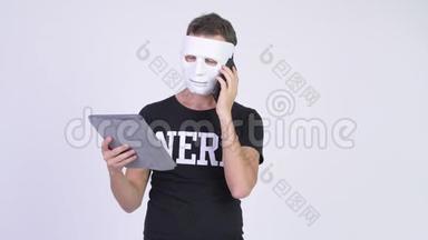 在使用手机和数码平板电脑时戴着白色面具的黑客