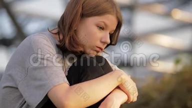 年轻的少女坐在公园里，抱着她的膝盖<strong>思念</strong>