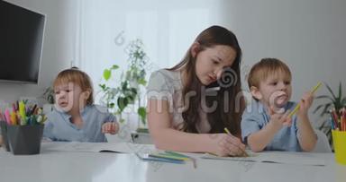 一位带着两个孩子在手机上说话的年轻母亲用<strong>铅笔画</strong>画，并帮助孩子们用<strong>彩色</strong>画画