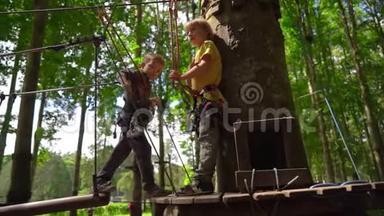在森<strong>林探</strong>险公园的树梢上，两个穿着安全带的小男孩在一条路线上爬起来