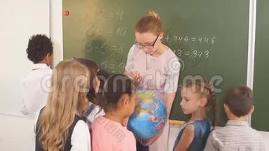 小学生和老师一起看地球仪上的地理课