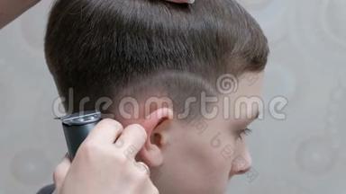 理发店里时髦的青少年发型。 一个专业的男理发师用<strong>剪发</strong>器在他`耳朵上剪条。