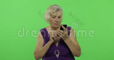 一位老年妇女在智能手机上交谈。 <strong>老奶奶</strong>笑了。 铬键