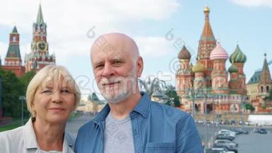这对老夫妇站在俄罗斯莫斯科`圣巴西尔大教堂和克里姆林宫钟楼的背景下