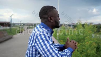 黑人站在公园围栏附近的城市海滨，欣赏城市景色。