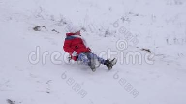 穿着红色夹克的快乐孩子穿着雪橇滑过雪地，笑了起来。 快乐的女孩在圣诞假期里玩耍